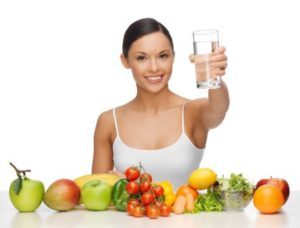 woman holding glass standing behind fruits 